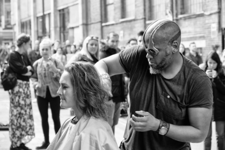 person giving another person a haircut in the street at an event